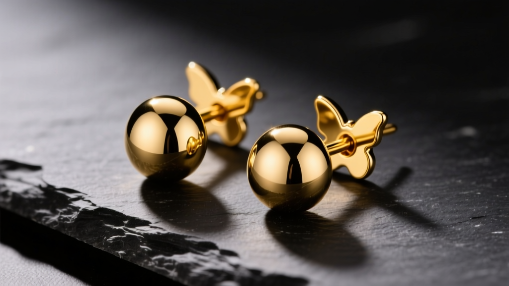 Round 14k yellow gold earring studs on dark slate, showing the polished dome and butterfly backing under warm studio lighting.