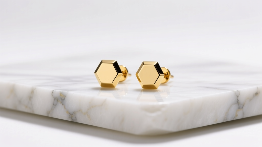 Flat lay of minimalist 14k yellow gold hexagon stud earrings resting on raw white marble, soft lighting highlighting sharp edges.
