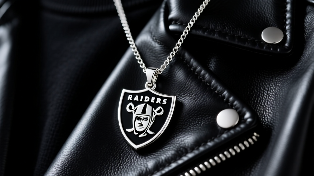 Sterling silver Las Vegas Raiders shield pendant on a 2mm curb chain resting on a black leather jacket under soft studio lighting.