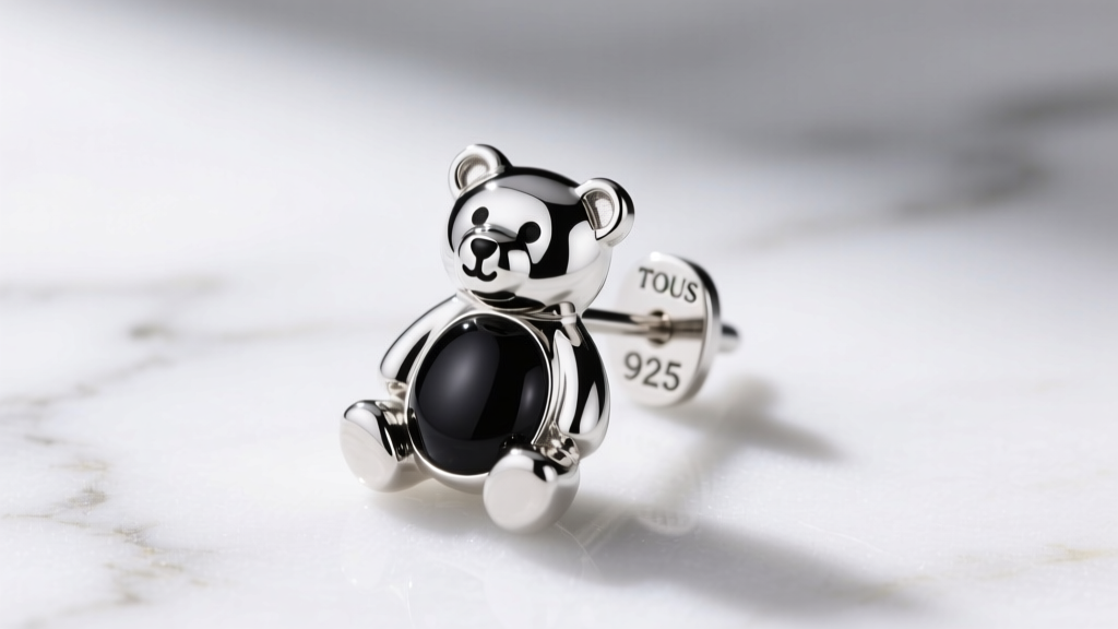 Macro shot of a sterling silver TOUS bear earring with black onyx belly on white marble, showing the 925 hallmark stamp clearly.