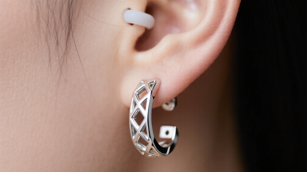Close-up of 20-gauge sterling silver dangle earring secured with silicone friction back on pierced earlobe, highlighting weight.