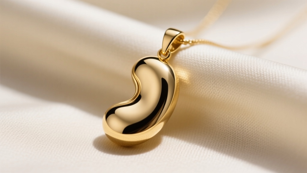 Polished 14k solid gold kidney bean pendant on raw silk, highlighting smooth asymmetric organic curves and high shine finish.