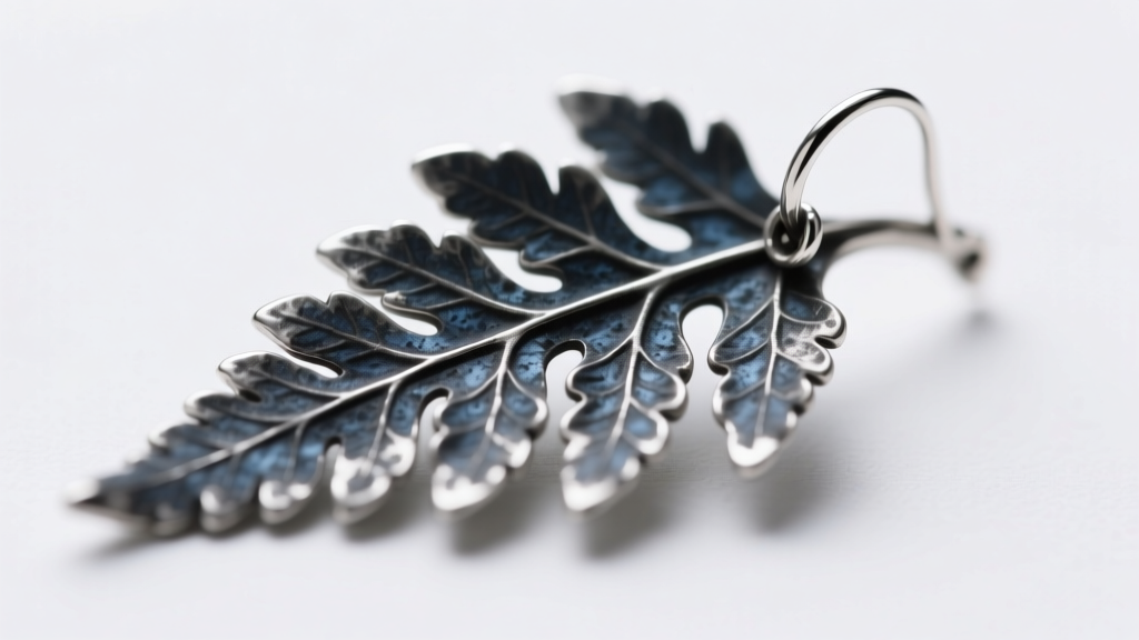 Macro shot of sterling silver fern leaf earring showing oxidation in deep crevices, highlighting textured metal.