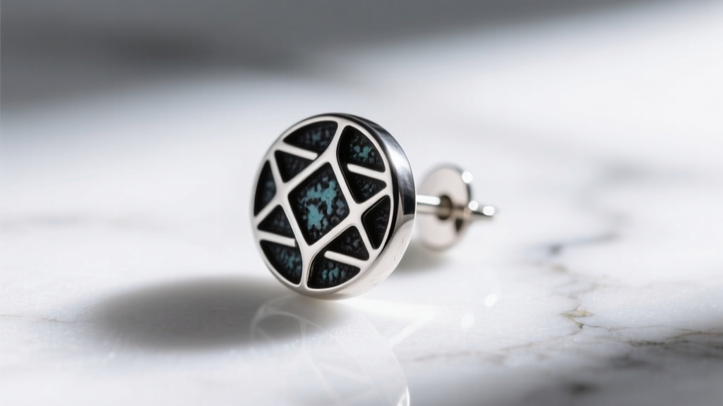 Macro photo of an oxidized sterling silver stud earring featuring dark patina detailing against a white marble background texture