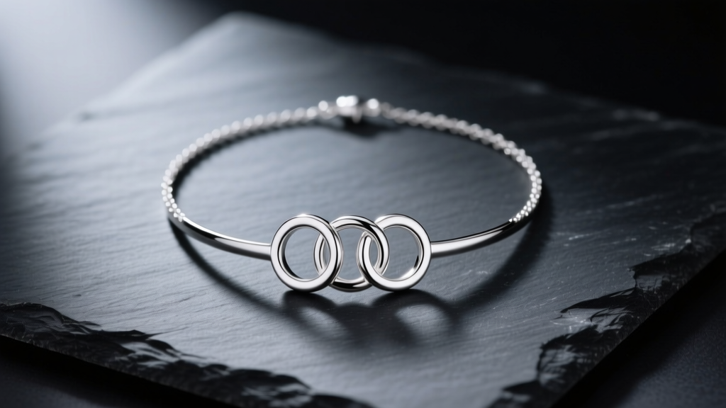 Flat lay of a 925 sterling silver Olympic rings necklace resting on dark slate, illuminated by soft directional studio lighting
