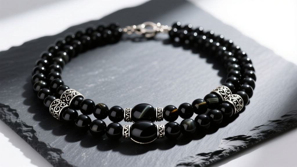 Flat lay of a black multi strand necklace featuring matte onyx beads and oxidized silver clasps resting on a dark slate surface