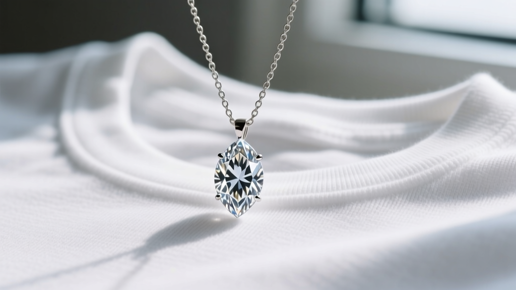 Macro shot of a sharp marquise diamond pendant on a 1.5mm box chain, resting against a soft white cotton crew neckline.