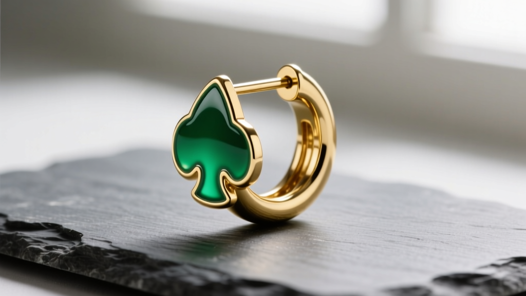 Close-up of a gold-plated Kate Spade hoop earring on slate, showing the glossy enamel spade charm and steel post.