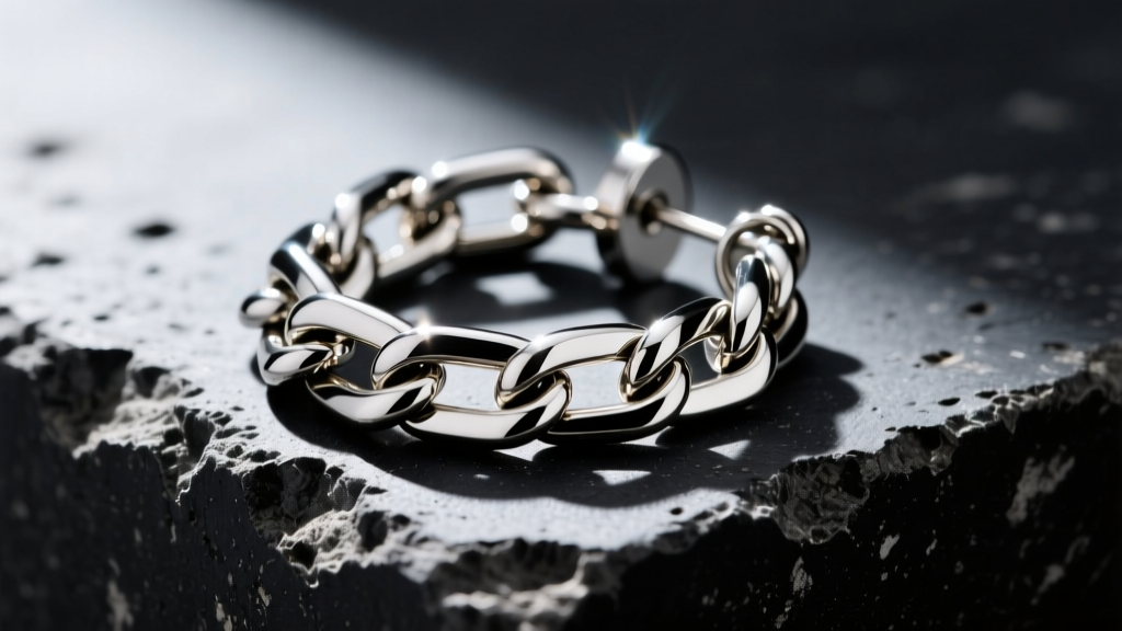 Macro shot of Alexander Wang rhodium-plated brass chain earring on black concrete, highlighting industrial hardware and clasp.