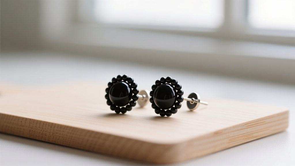 Handmade beaded stud earrings featuring matte onyx beads on flat-pad titanium posts resting on a clean wooden crafting mat