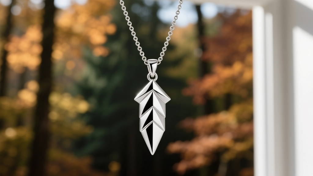 Silver arrowhead pendant hanging from a 2mm oxidized sterling rolo chain, photographed against a softly blurred forest background.