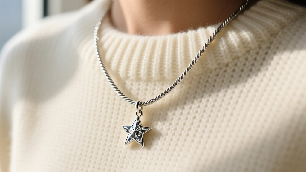 Close-up of a delicate 18-inch sterling silver cable chain with a small celestial star pendant on a soft cream knit sweater.