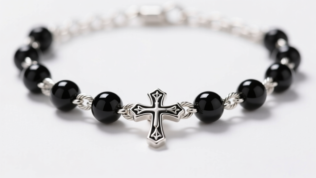 Macro shot of a 1.5mm sterling silver cable chain interspersed with matte onyx beads and a small cross pendant in soft light