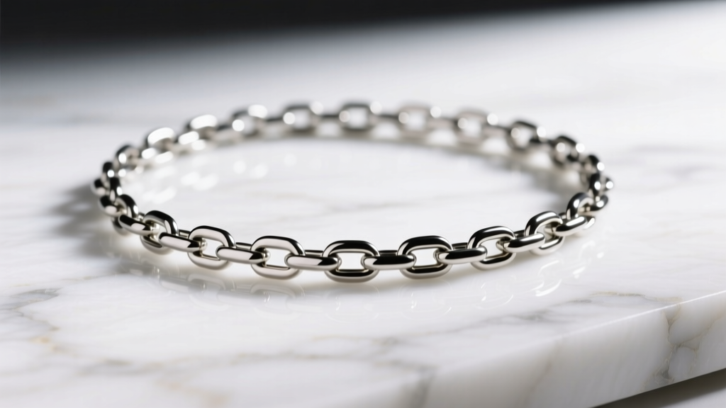 Macro shot of a 3mm steel figaro chain draped over white marble, highlighting the alternating link pattern in bright studio light