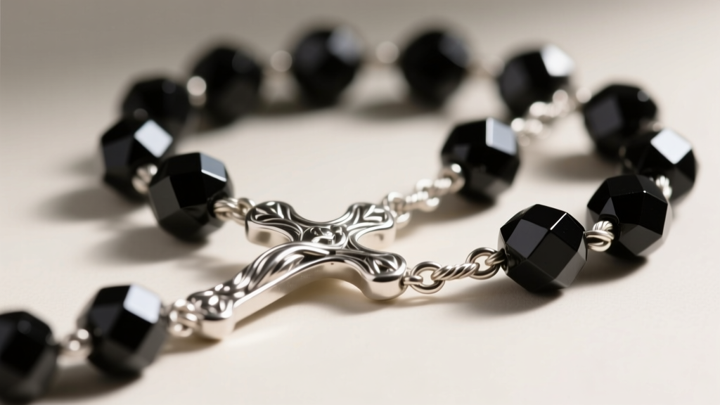 Macro shot of sterling silver rosary centerpiece, showing 1.5mm cable chain connecting to smoothly faceted black onyx decade beads.