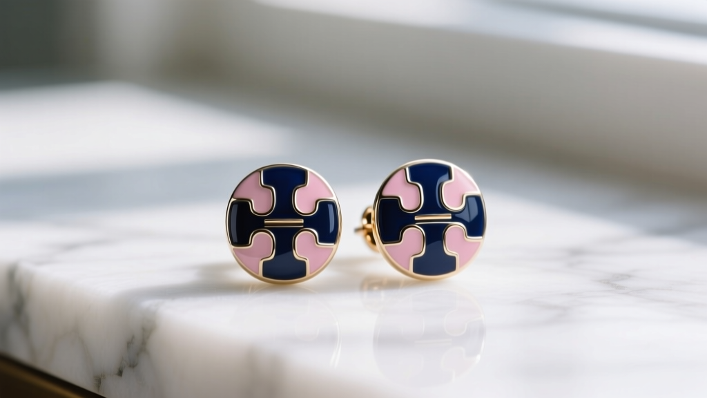 Classic Tory Burch Miller enamel stud earrings in navy and blush pink resting on white marble under soft natural window lighting.
