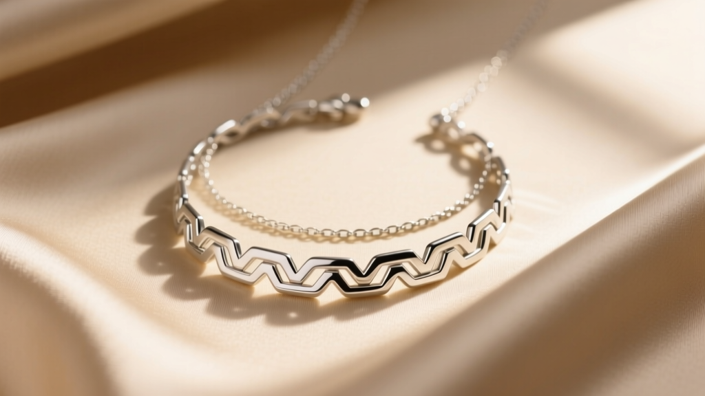 Sterling silver Greek key necklace layered with a fine chain over beige silk, captured in soft warm directional window light.