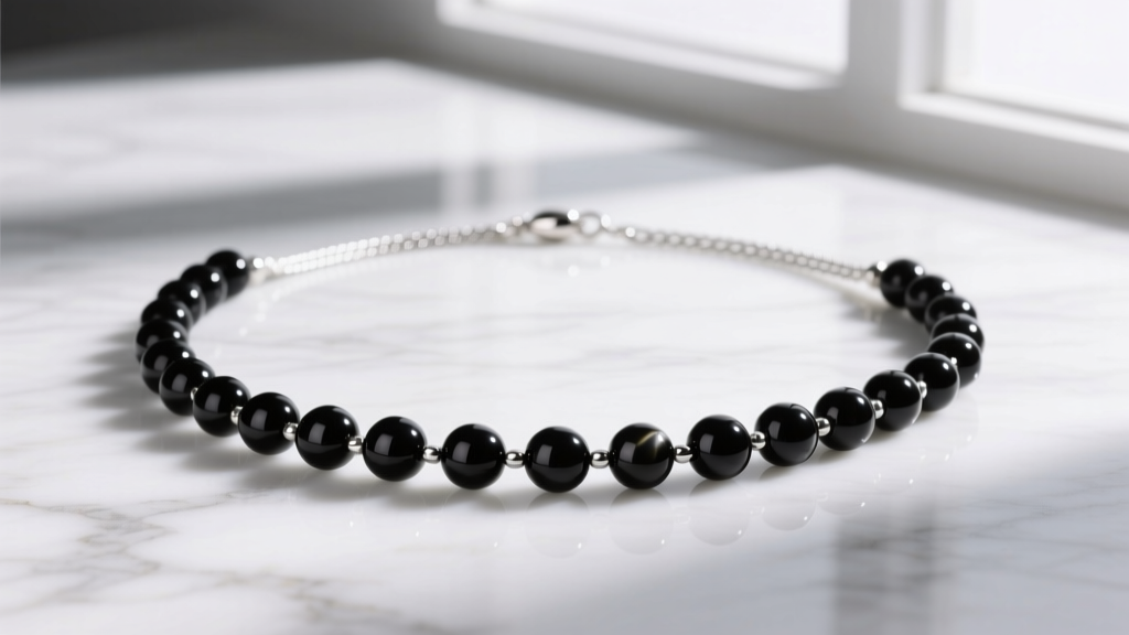 Flat lay of a rosary fashion necklace with 6mm black onyx beads and a 1.5mm sterling silver cable chain on white marble