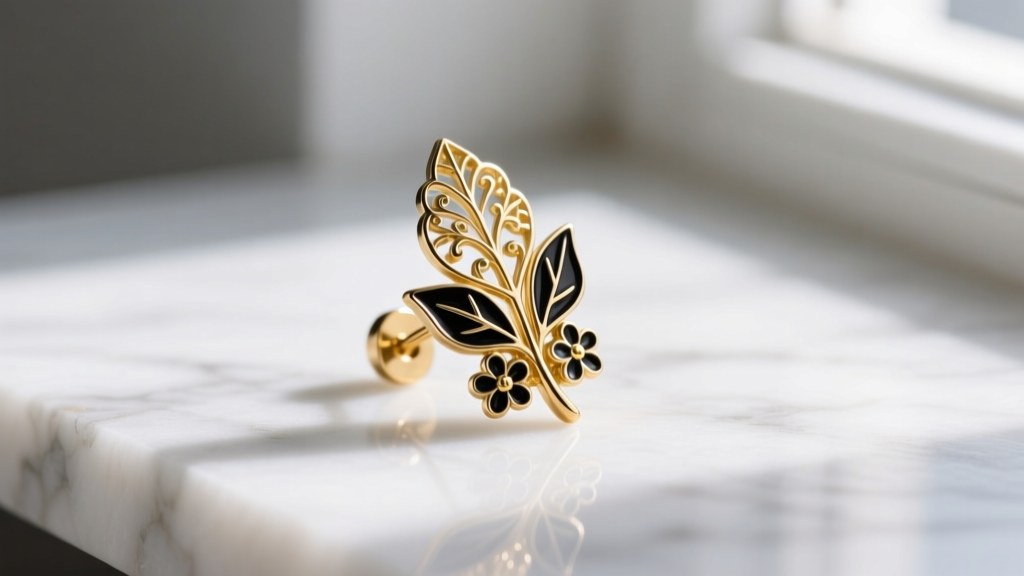 Side profile of a gold-plated brass botanical stud earring with black vitreous enamel accents displayed on a white marble surface.