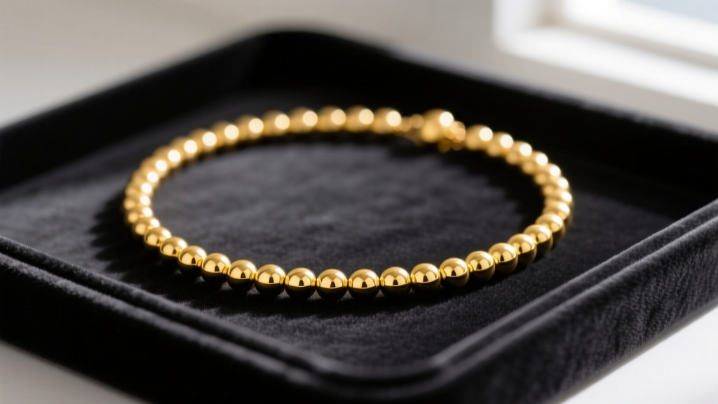 Close-up of a seamless 14k yellow gold bead necklace with 4mm high-polish beads resting on a dark velvet jewelry display tray