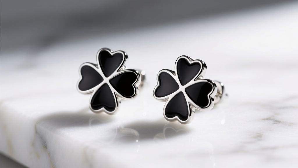 Close-up of 925 sterling silver four-leaf clover stud earrings with black cold enamel inlay resting on a white marble surface.