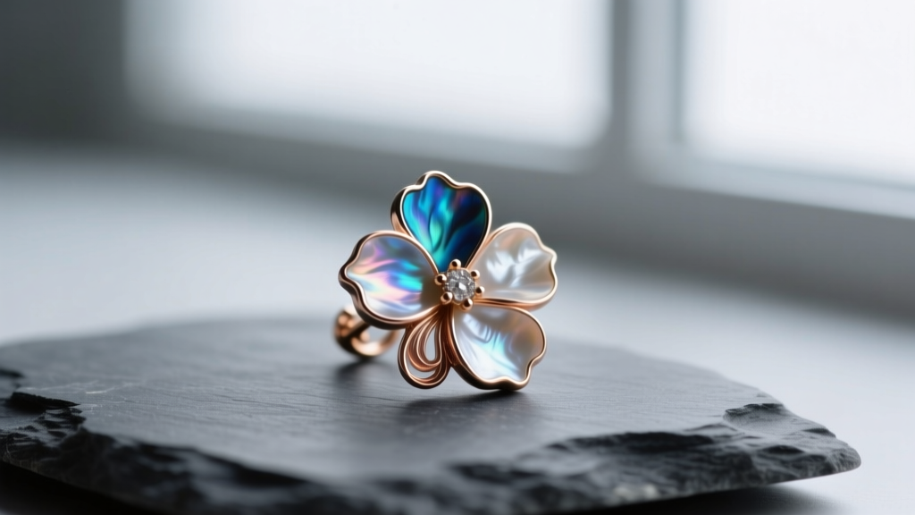 Macro shot of a carved mother of pearl floral earring revealing thick nacre layers, resting on a dark grey slate stone background.