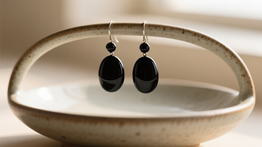 Close-up of matte black onyx bead drop earrings hanging from a ceramic dish, soft directional lighting highlighting texture.