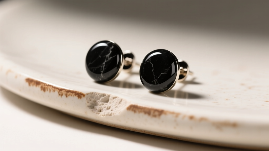 Black Oltu stone stud earrings on unglazed porcelain showing a brown testing streak, captured under bright and diffused studio lighting.