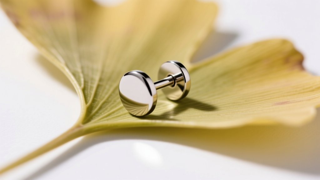 Macro shot of a 20g titanium post on a ginko leaf stud, featuring a flat disc back for comfortable, snag-free wear on the lobe.