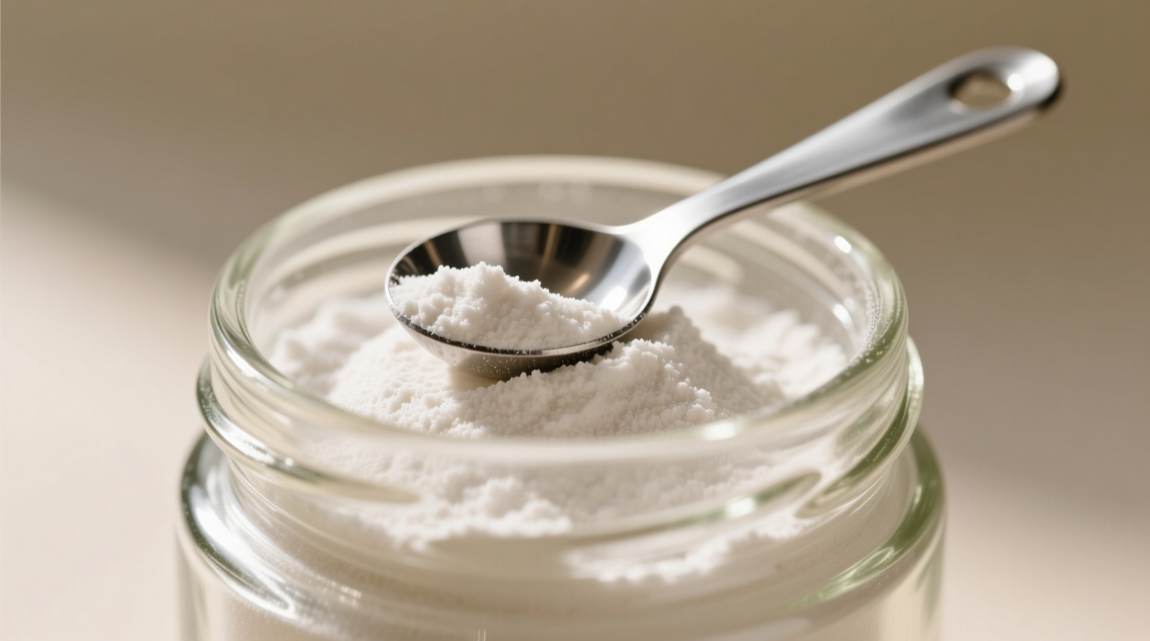 Raw potato starch in glass container with measuring spoon