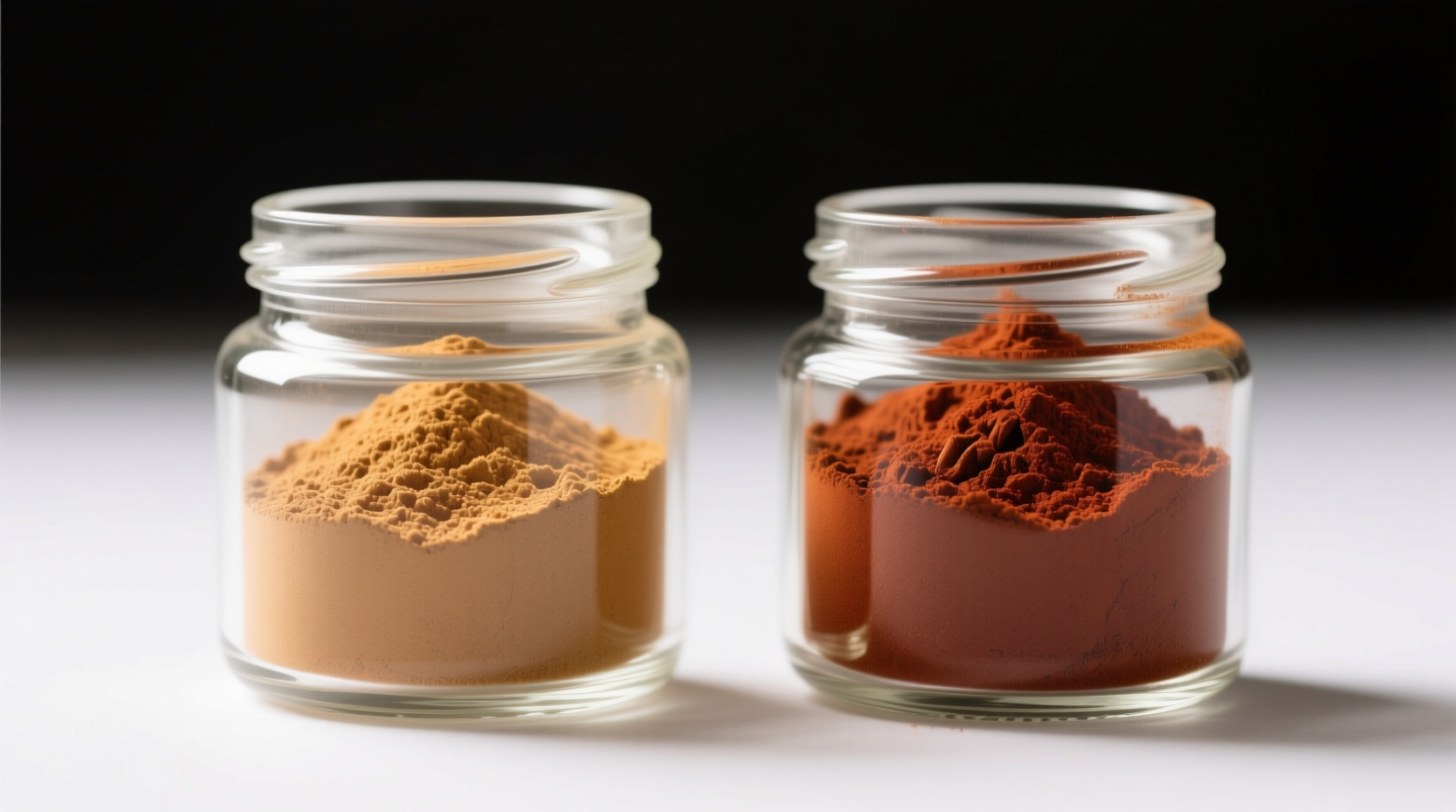 Side-by-side comparison: light tan Ceylon cinnamon powder versus dark reddish cassia powder in glass jars