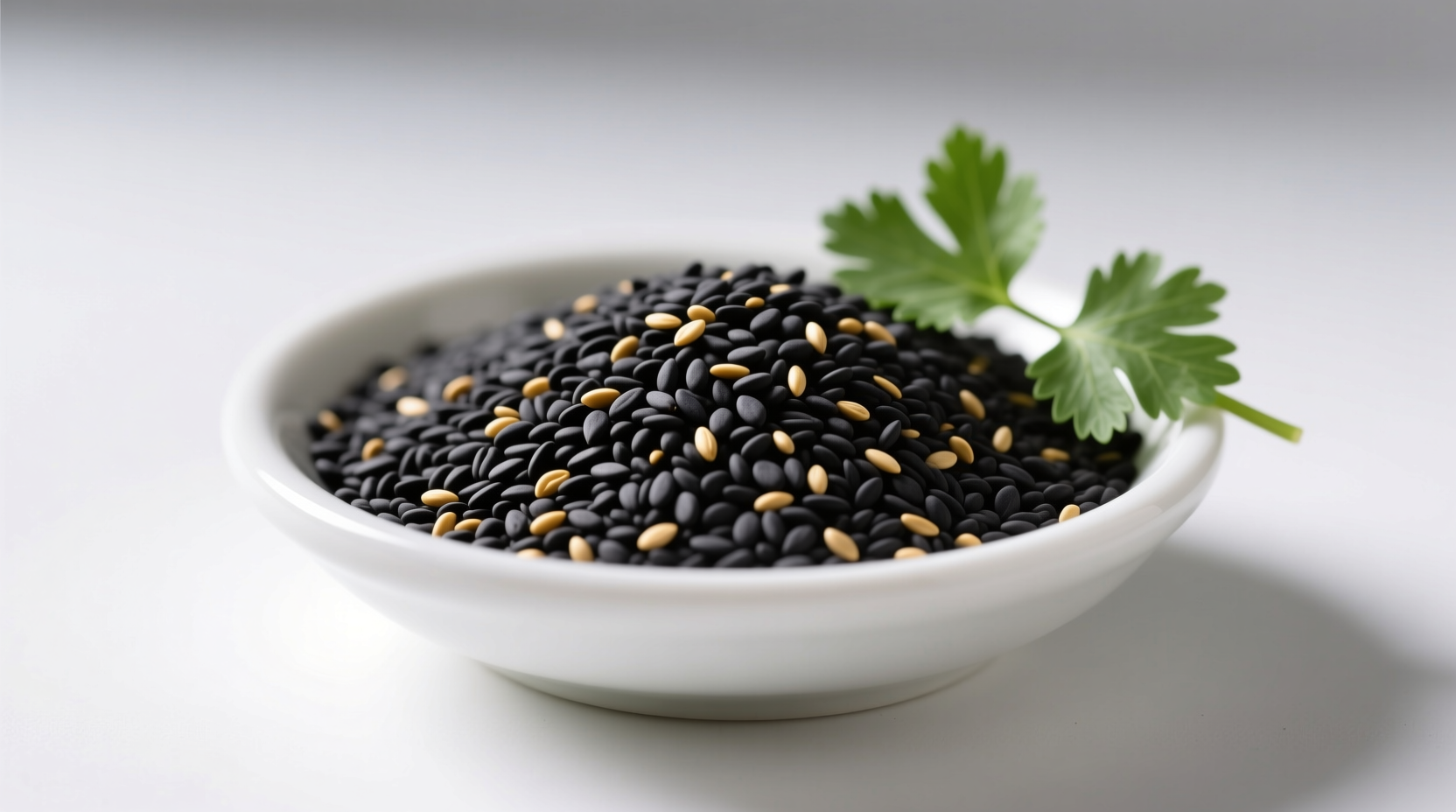 Close-up of black sesame seeds in a wooden bowl beside fresh greens and a mortar, showing their deep charcoal color and natural texture