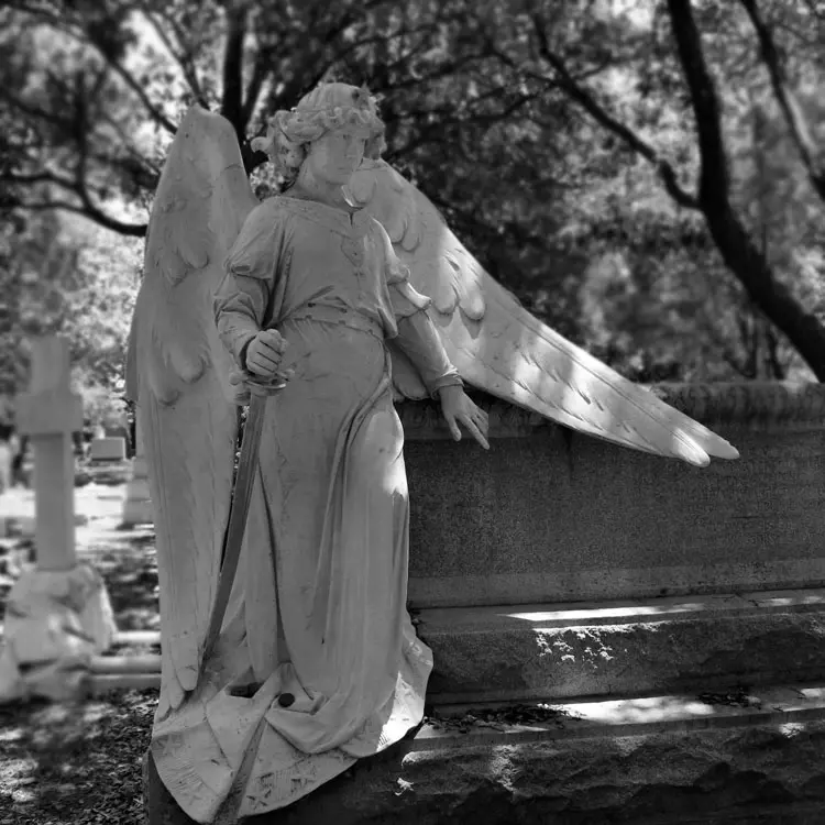 Stone female angel statue standing beside the grave marble cemetery sculpture