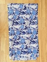 Kain yang indah menampilkan pola bunga-bunga biru dengan bunga dan daun di latar belakang putih, menciptakan kesan tradisional yang elegan.
