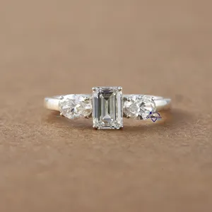 Exclusive three stone solitaire diamond ring in 14 kt white gold with lab grown emerald and oval cut diamonds with VVS clarity