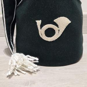 Ceci est un chapeau bicorne en feutre de laine vert foncé avec une bordure blanche et un pompon décoratif, doté d'un emblème de corne de cheval. - Product Image 4