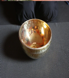 Un pequeño cuenco de latón pulido con un interior altamente reflectante se asienta sobre una superficie oscura y texturizada. - Product Image 1