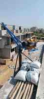 Chantier de construction sur toit : Camion-grue Metro Industries (300 tonnes) levant des sacs de ciment sur un chantier de construction en béton, ciel clair et lumineux