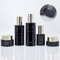 Ensemble de soins de la peau en verre noir élégant et luxueux avec des bouchons dorés polis, flacons rechargeables pour sérum anti-âge et crème pour le visage de qualité supérieure