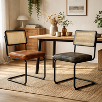Chaise de salle à manger industrielle moderne en cuir de buffle, dossier en rotin, structure en métal noir, non pliable |   Conception en cantilever fabriquée en Inde AKKU