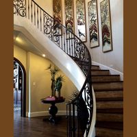 Escalier incurvé en fer forgé de style provincial français sur mesure avec des détails de feuilles en spirale et une finition bronze foncé