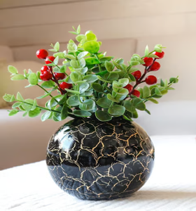 Vase rond en métal noir avec finition craquelée dorée et feuillage vert. Disponible à prix de gros. - Product Image 1