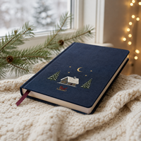 Journal de Noël personnalisé LABON, couverture rigide en lin bleu marine, broderie cabane enneigée, lune, étoiles, traîneau, pages lignées, ruban