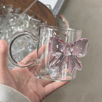 Taza de cristal transparente personalizable con lazo rosa y accesorio en forma de corazón con mango de cuentas