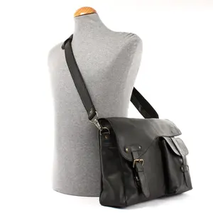 Một túi Messenger da màu đen với túi bên ngoài, dây đeo vai có thể tùy chỉnh và có thể tháo rời và một nắp được bảo đảm bằng cách Đóng Snap