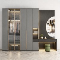 Armoire grise moderne autoportante avec coiffeuse, miroir LED, portes vitrées et poignées dorées pour suite d'hôtel