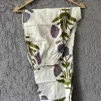 Ensemble de vêtements de détente élégants avec motifs de fleurs violettes et de feuilles vertes sur fond blanc, créant un design botanique frais.