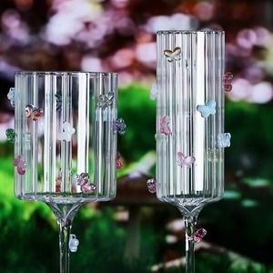 La transparencia de una copa de vino de cristal con un detalle de mariposa crea un contraste visualmente atractivo contra los vinos de colores intensos. - Product Image 3