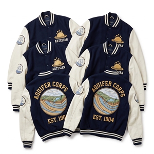 Chaqueta Letterman al por mayor, azul verdoso, de lana, estilo universitario, con bordado 'Subterranean Waters Rain Cistern' y mangas de cuero color canela, tipo bomber. - Product Image 2
