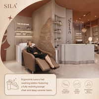 Présentation du mobilier de salon de luxe du Qatar : fauteuil de pédicure crème, bassin pour les pieds ambré, mur en pierre brute et bureau ondulé pour institut de beauté